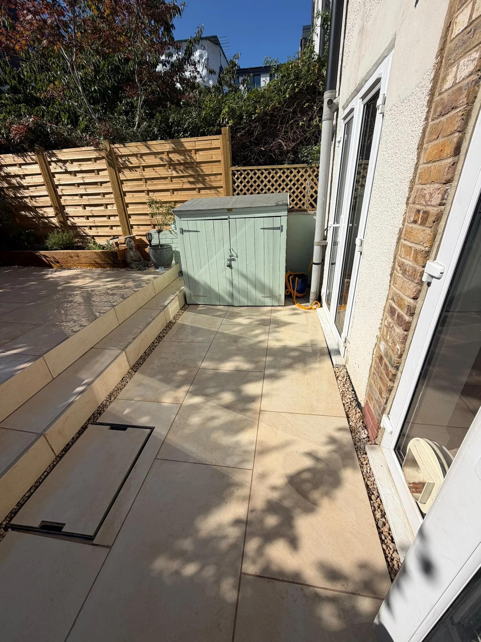 Shed Installation Greenwich New porcelain patio with French drain gravel drainage channel, trellis fence panel and sage green garden shed in Greenwich
