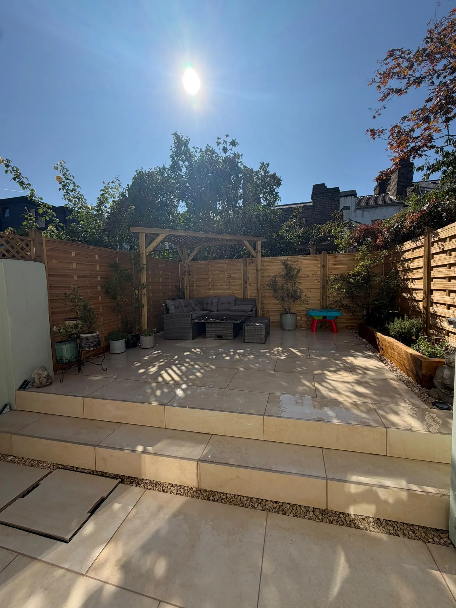 Timber Pergola Greenwich Custom-built timber pergola over a rattan corner sofa on a new porcelain patio in a Greenwich garden landscaping project
