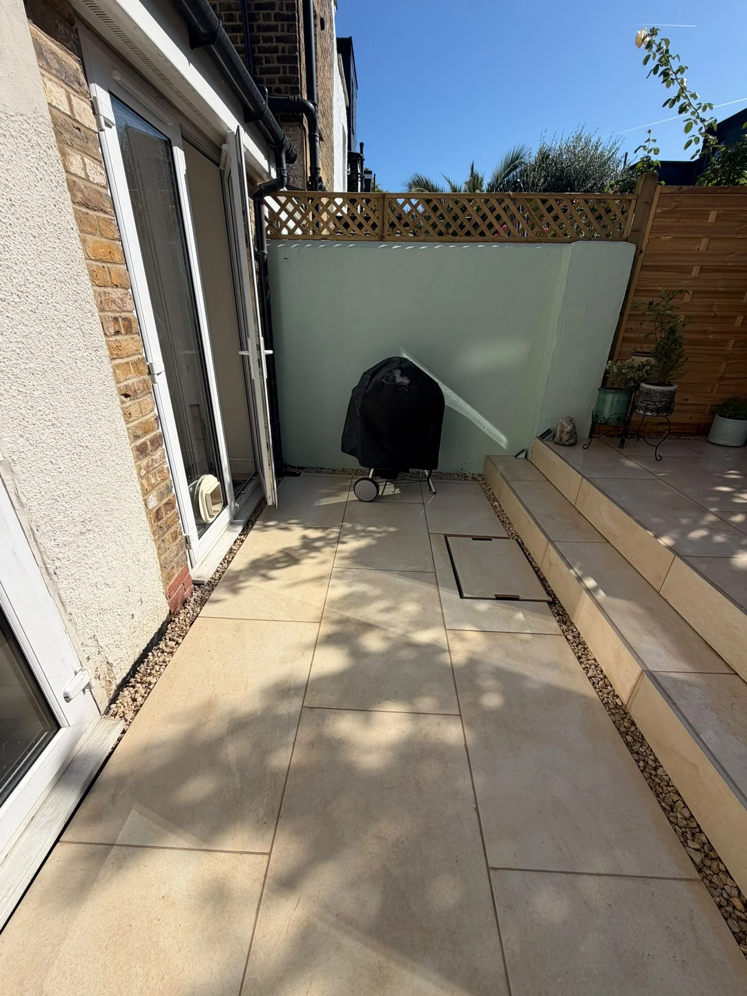 New trellis panel above the gravel French drain drainage channel along new porcelain patio in Greenwich