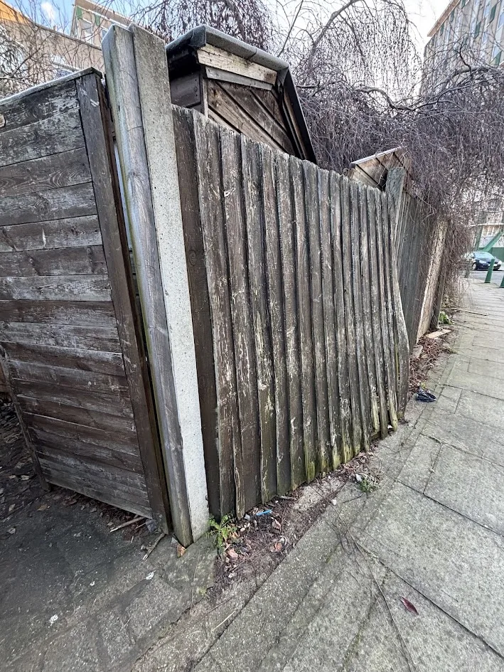 Leaning, rotten boundary fence before repair